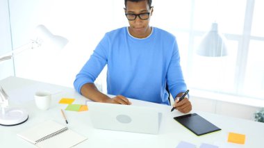 Afro-Amerikan yaratıcı tasarımcı çizim ile grafik tablet üstünde Laptop