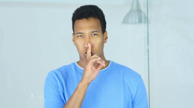 Genç Afro-Amerikan adam, dudaklarında parmak sessizliktir jesti