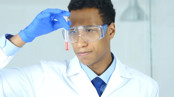 Científico investigador, doctor mirando la solución roja en tubo de ensayo en laboratorio —  Fotos de Stock