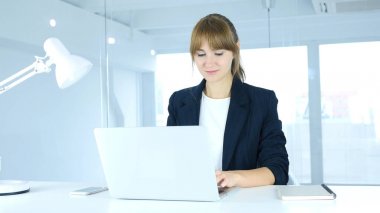 Genç kadın ofiste dizüstü bilgisayarda çalışma