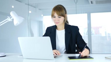 Genç kadın bir bilgisayar için çizim tabletiyle çalışan tasarımcı