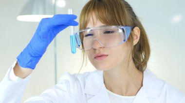 Kadın araştırma bilim adamı, Doktor tüp laboratuvar mavi çözümde bakarak