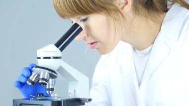 Kadın kimyacı, bilimsel laboratuarda mikroskop kullanarak açmaktadır