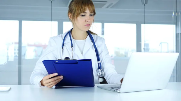 Jovem Médica Lendo Relatórios Médicos e Trabalhando no Laptop — Fotografia de Stock