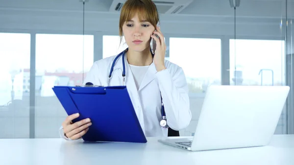 Ung kvinna läkare innehav medicinska rapporter, prata telefon — Stockfoto