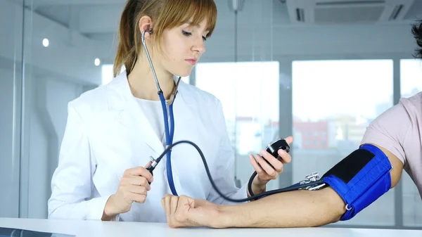年轻女医生检查病人在诊所的血压 — 图库照片