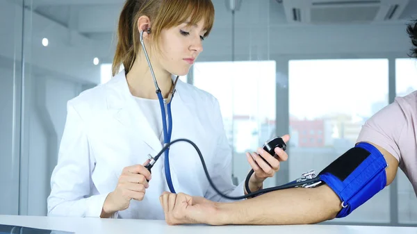 Jovem Médica Verificando a Pressão Arterial do Paciente na Clínica — Fotografia de Stock