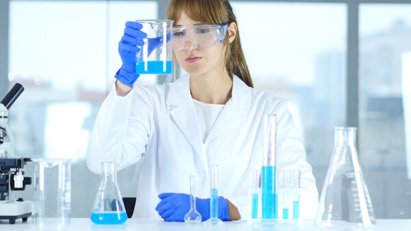 Female Research Scientist Looking at Solution in Beaker in Laboratory, Reaction
