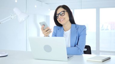 Smartphone, genç iş kadını tarama online iş yerinde kullanarak