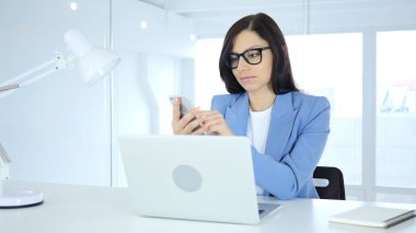 Smartphone, genç iş kadını tarama online iş yerinde kullanarak