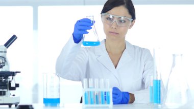 Bilim adamı, Doktor laboratuvar şişesi mavi çözümde bakarak