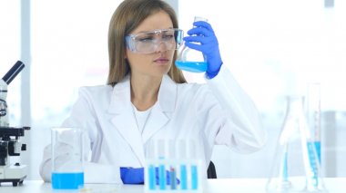 Kadın araştırma bilim adamı şişeye laboratuvar mavi çözümde bakarak