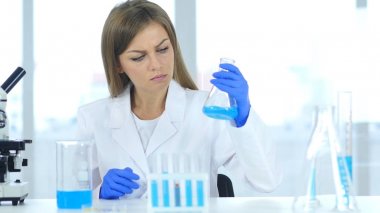 Kadın araştırma bilim adamı şişeye laboratuvar mavi çözümde bakarak