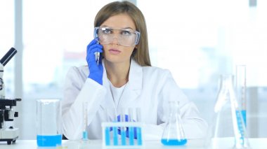 Koruyucu gözlük laboratuvar telefonda konuşurken kadın bilim adamı