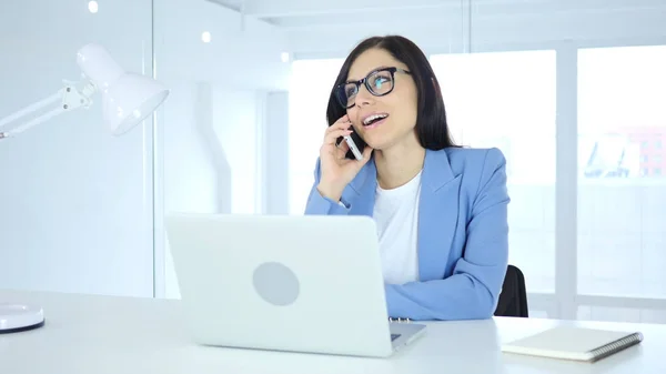 Hablando por teléfono, una joven empresaria atiende una llamada en el trabajo —  Fotos de Stock