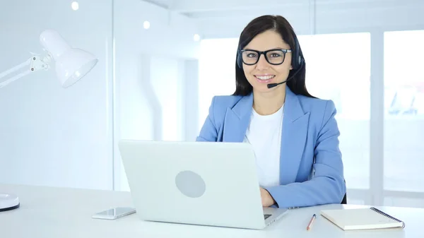 Jeune femme d'affaires souriant vers la caméra tout en travaillant sur ordinateur portable — Photo