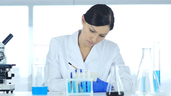 Scientist Writing Results of Research in Laboratory