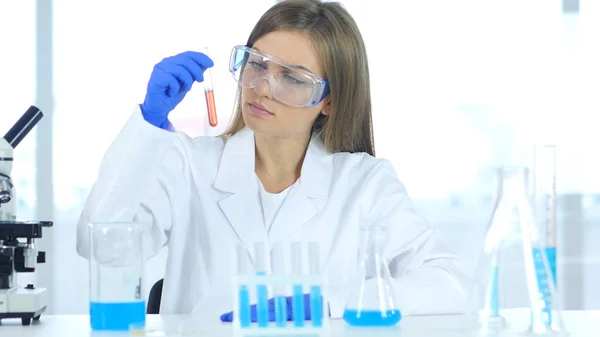 여성 연구원 실험실에서 테스트 튜브에 빨간 솔루션 보고 — 스톡 사진
