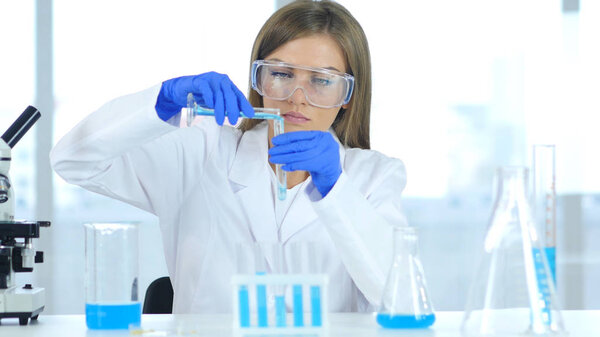 Female Scientist Working in Laboratory, Pouring Solution in Test Tube