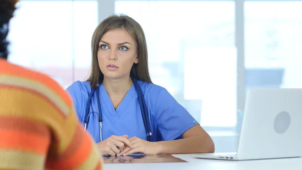 Jovem médica discutindo problemas com o paciente — Fotografia de Stock