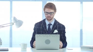 Düşünme ve dizüstü bilgisayarda çalışan Kızıl saçlı dalgın adam