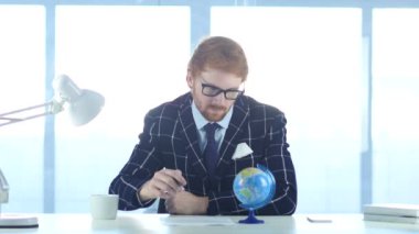 Kızıl saçlı işadamı okuma dünya küre dikkat