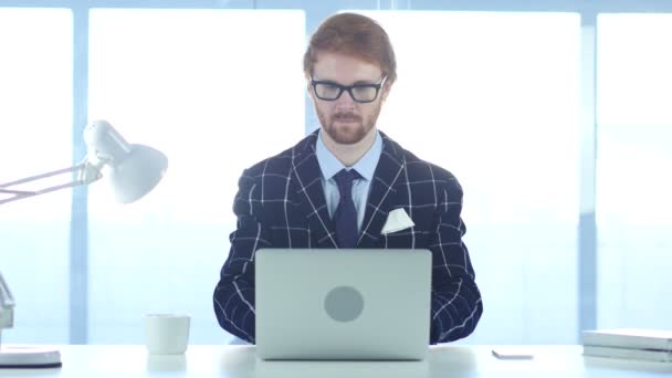 Empresário ruivo sorrindo para câmera enquanto trabalhava no laptop — Vídeo de Stock