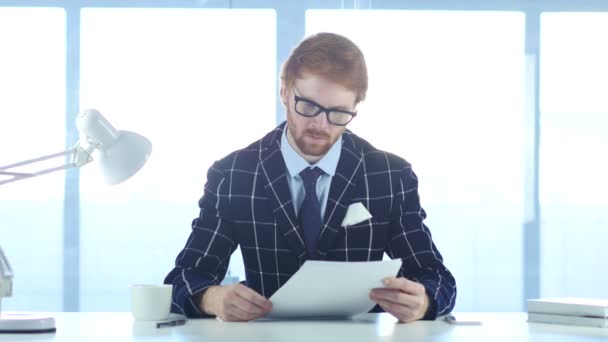 Ernster Mann, der bei der Arbeit Doppelgänger liest, rote Haare — Stockvideo