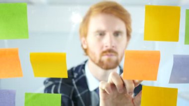 Yapışkan notlar ofis camının bağlı çalışan Kızıl saçlı işadamı