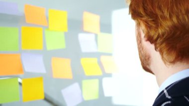 Yapışkan notlar, arkadan görünüm üzerinde çalışan dalgın Redhead işadamı