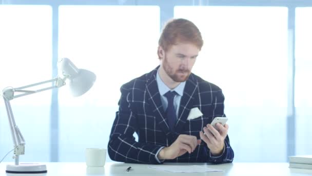 スマート フォンを使用したオンラインの閲覧、赤い毛を持つ男 — ストック動画