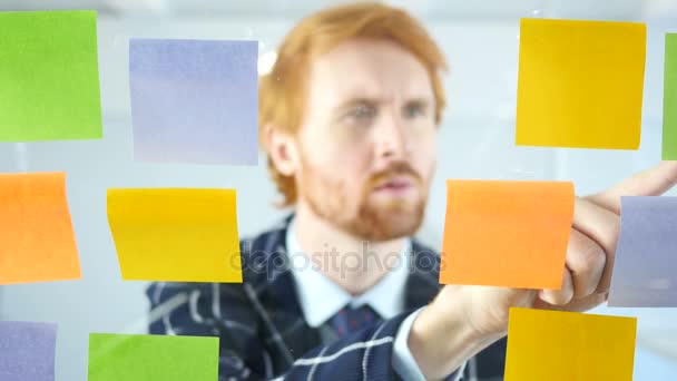 Redhead Man Working On Sticky Notes Attached on Glass in Office — Stock Video