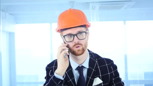 Борода інженер-архітектор розмовляє по телефону, відвідуючи дзвінок на роботі — стокове відео