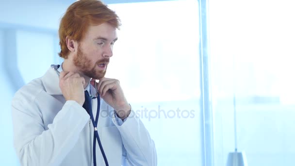 Médecin assis dans une clinique avec stéthoscope aux oreilles — Video