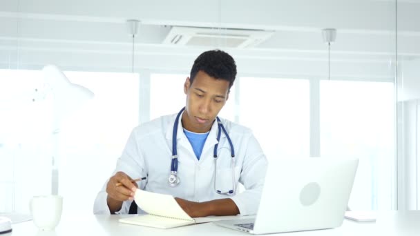 Афроамериканский врач, пишущий медицинские отчеты о пациентах, медицине — стоковое видео