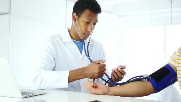 Médico afroamericano revisando la presión arterial del paciente en la clínica — Vídeo de stock