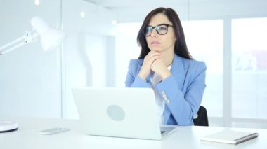 Düşünme ve dizüstü bilgisayarda çalışan genç iş kadını