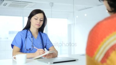 Doktor yazma tıp ve önünde oturan hasta ile konuşmak