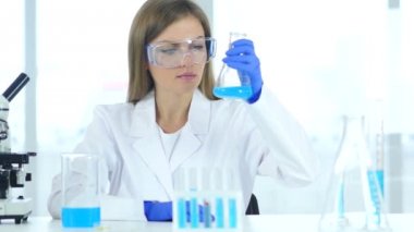 Kadın araştırma bilim adamı şişeye laboratuvar mavi çözümde bakarak