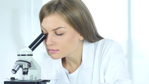 Женский научный исследователь, работающий над микроскопом в лаборатории — стоковое видео