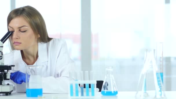 Cientista de Pesquisa Feminina Olhando para Solução Azul em Frasco em Laboratório — Vídeo de Stock