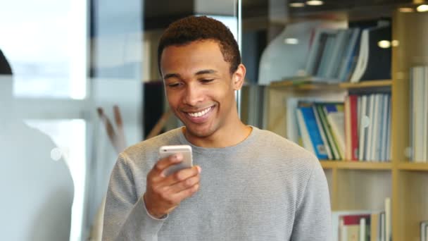 Młody człowiek afro-amerykański, przeglądania stron internetowych na Smartphone — Wideo stockowe