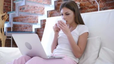 Genç adam kahve içme ve dizüstü bilgisayar üzerinde çalışan portre