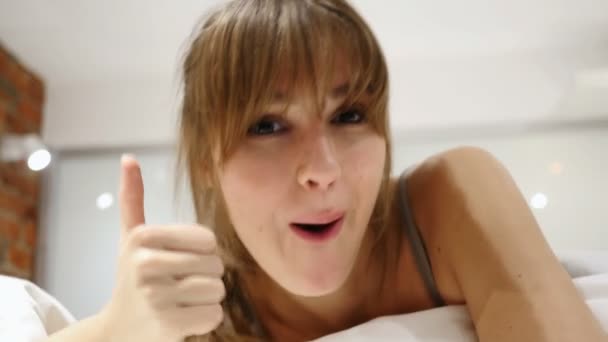 Kciuk w górę przez kobietę leżącą w łóżku, zbliżenie na twarz — Wideo stockowe