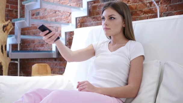 O femeie se uită la televizor, schimbă canalele cu telecomandă — Videoclip de stoc