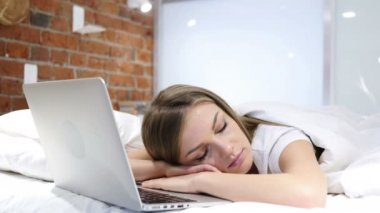 Dizüstü bilgisayar, iş sonra yakınındaki yatakta uyuyan kadın