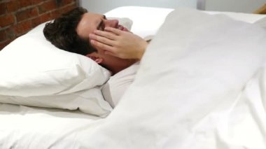 Geceleri yatakta baş ağrısı ile gergin adam üzgün