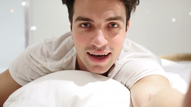 A csinos, fiatal férfi, az ágyban fekve rendben gesztus — Stock videók