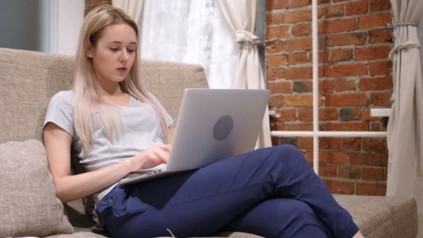 Молодая женщина празднует успех во время работы над ноутбуком — стоковое видео