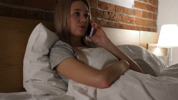 Женщина в постели разговаривает по мобильному телефону, обсуждение — стоковое видео